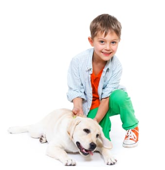Cute little boy kneeling with his puppy labrador smiling at camera on white background