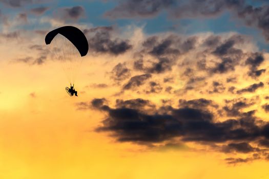 silhouette of unidentified skydiver parachutist on sky with sunset