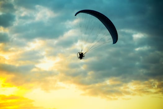 silhouette of unidentified skydiver parachutist on blue sky on sunset