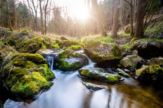 Falls on the small mountain river in a wood in spring with light leak and sun flare 