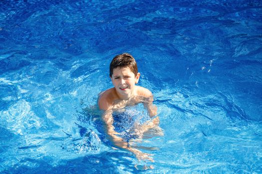 Boy in the home garden swimming pool with clear water