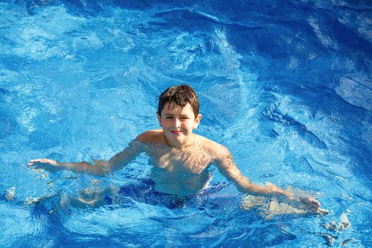 Boy in the home garden swimming pool with clear water