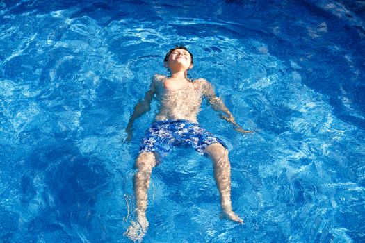 Boy in the home garden swimming pool with clear water