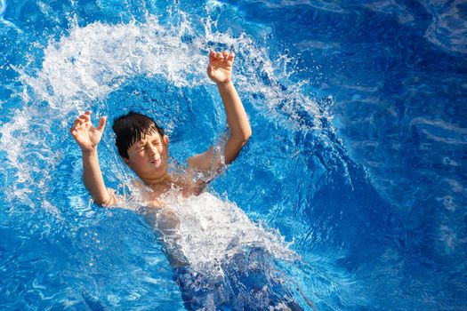 Boy jumping in the home garden swimming pool with clear water