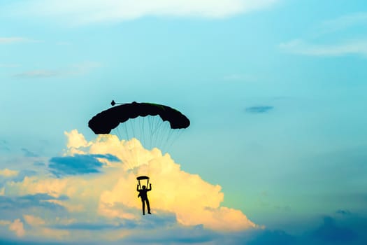 silhouette of unidentified skydiver parachutist on blue sky on sunset