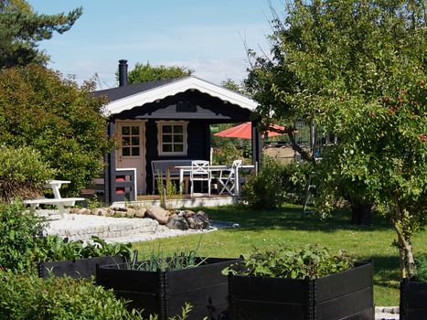 Wooden bungalow cabin painted black in a beautiful garden