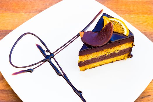 Chocholate orange cake on a white plate on wooden surface.