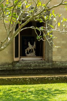 Quiet village lane leading away from the camera between stone walls covered with lush green foliage and vegetation in Bali showing the relaxed tropical lifestyle