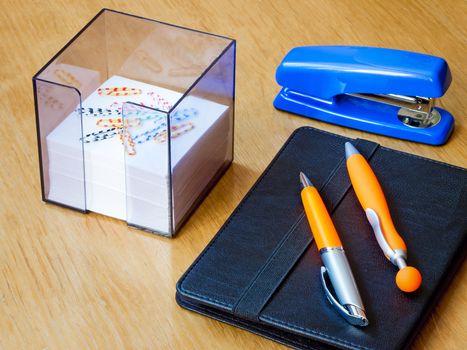 Two handles of bright orange color for the letter, the laptop and scratch paper in the container. Are photographed on a table surface.