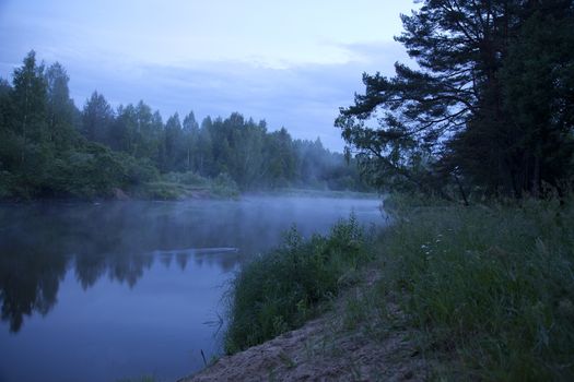 Landscape with forest, river and mist in the evening