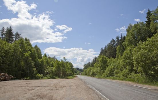 Summer lanscape with country road, trees and clouds