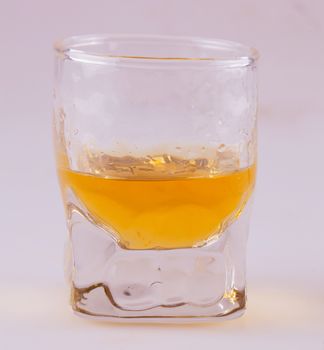 Whisky in a small glass over white background