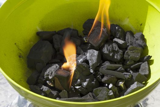 Burning carbon in a green barbeque, close up of fire