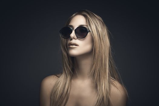 Beauty portrait of sexy blonde woman with sunglasses against grey background