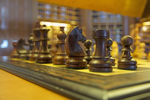 Wooden chess pieces on a chessboard in a ship's library