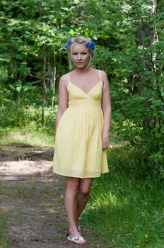 Young beautiful lady in yellow dress in green forest
