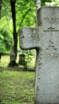 granite grave cross on a background of lush green 
