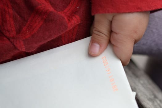 child's hand holding an envelope