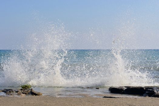 The waves breaking on stony beach, forming a spray