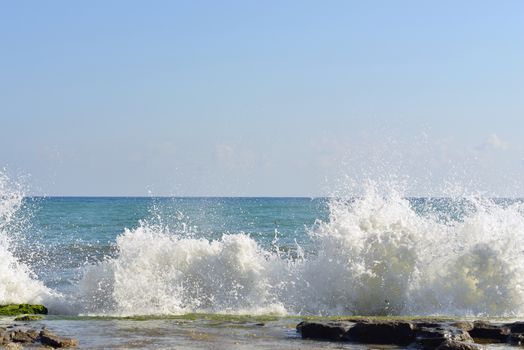 The waves breaking on stony beach, forming a spray