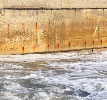 Seawater and the old concrete wall. Water obstacle