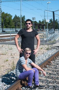 Shot of two guys on train tracks, focus on man in black