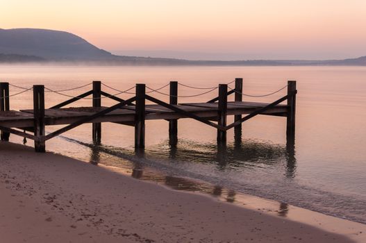 Dock on calm water at sunrise in winter