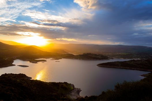 Landscape of sunset on the lake with the sun between the mountains