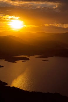 Landscape of sunset on the lake with the sun between the mountains