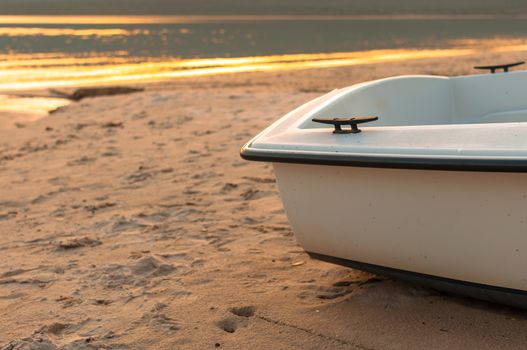 the stern of a small boat on the beach in a spring sunset