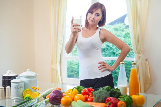 Young asian woman drinking milk in kitchen