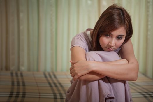 Asian sad woman sitting on the bed in bedroom