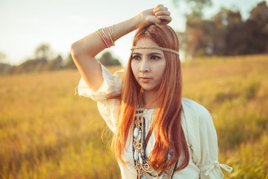 Hippie woman posing in golden field on sunset