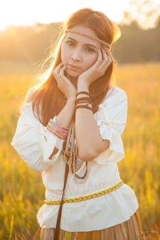 Hippie woman posing in golden field on sunset