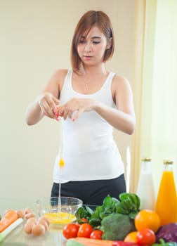 Young asian woman hands breaking an egg