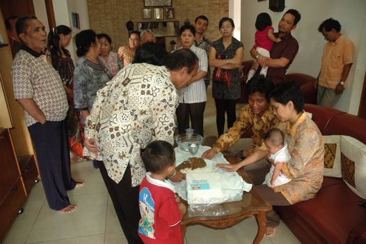 bandung, indonesia-december 19, 2010: family gathering together inside the house to celebrate baptism ceremonial.