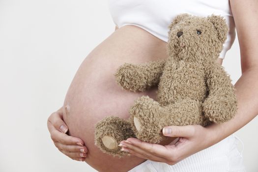 Close Up Of Pregnant Woman Holding Teddy Bear