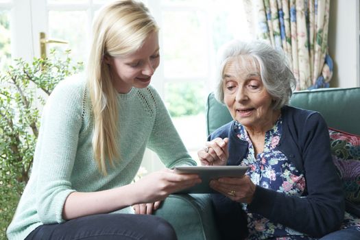 Granddaughter Showing Grandmother How To Use Digital Tablet