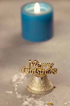 Christmas bells near burning candles on a snowy background