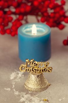 Christmas bells near burning candles on a snowy background