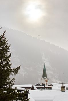 Church tower at Leukerbad by foggy winter, Switzerland