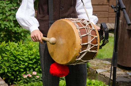 Drummer play folk music with drum and stick in rural village party.