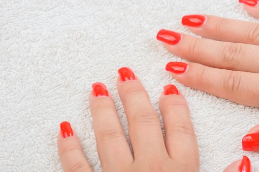 Female fingers with red enamel on white towel