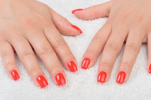 Female fingers with red enamel on white towel