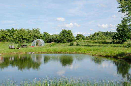 village big pond and greenhouse in summer nature