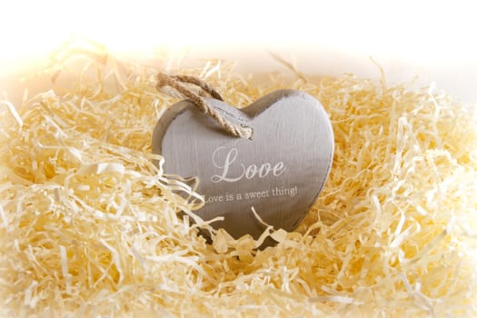 single brown wooden love heart in a love nest made of straw inscribed love is a sweet thing