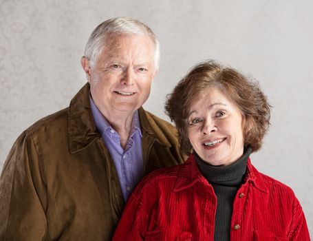 Adorable white senior citizen couple on gray background