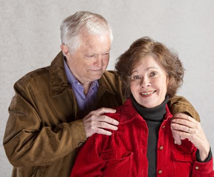 Cute mature couple hugging over gray background