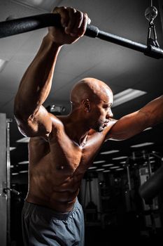 Fit male body builder working out  using a resistance cable weight machine.