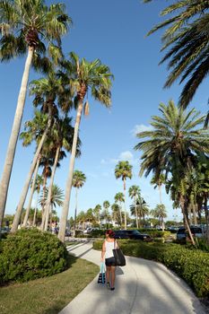 Woman walking on a pathway with Florida palm trees all around.